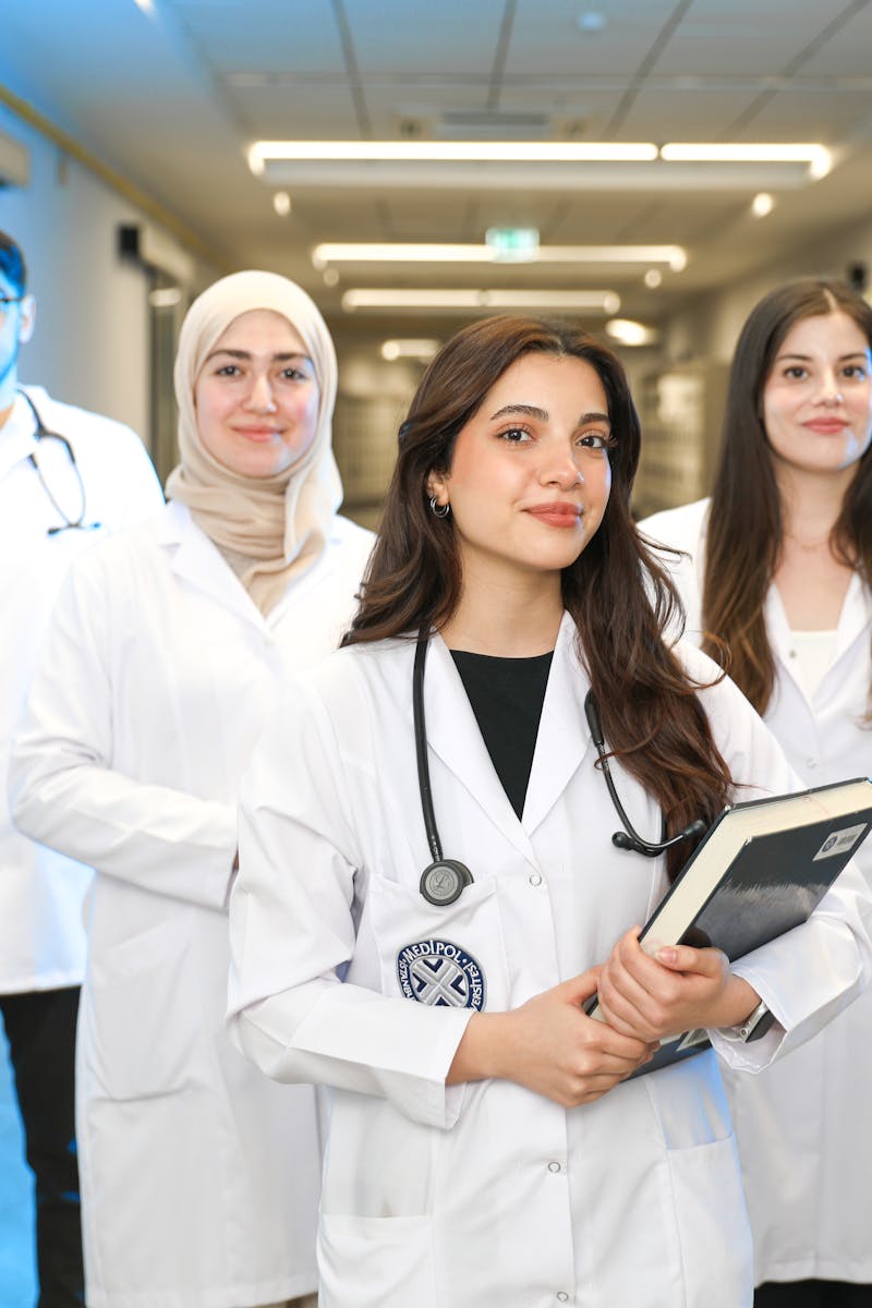Group of diverse medical students wearing lab coats in university corridor, representing future healthcare professionals.